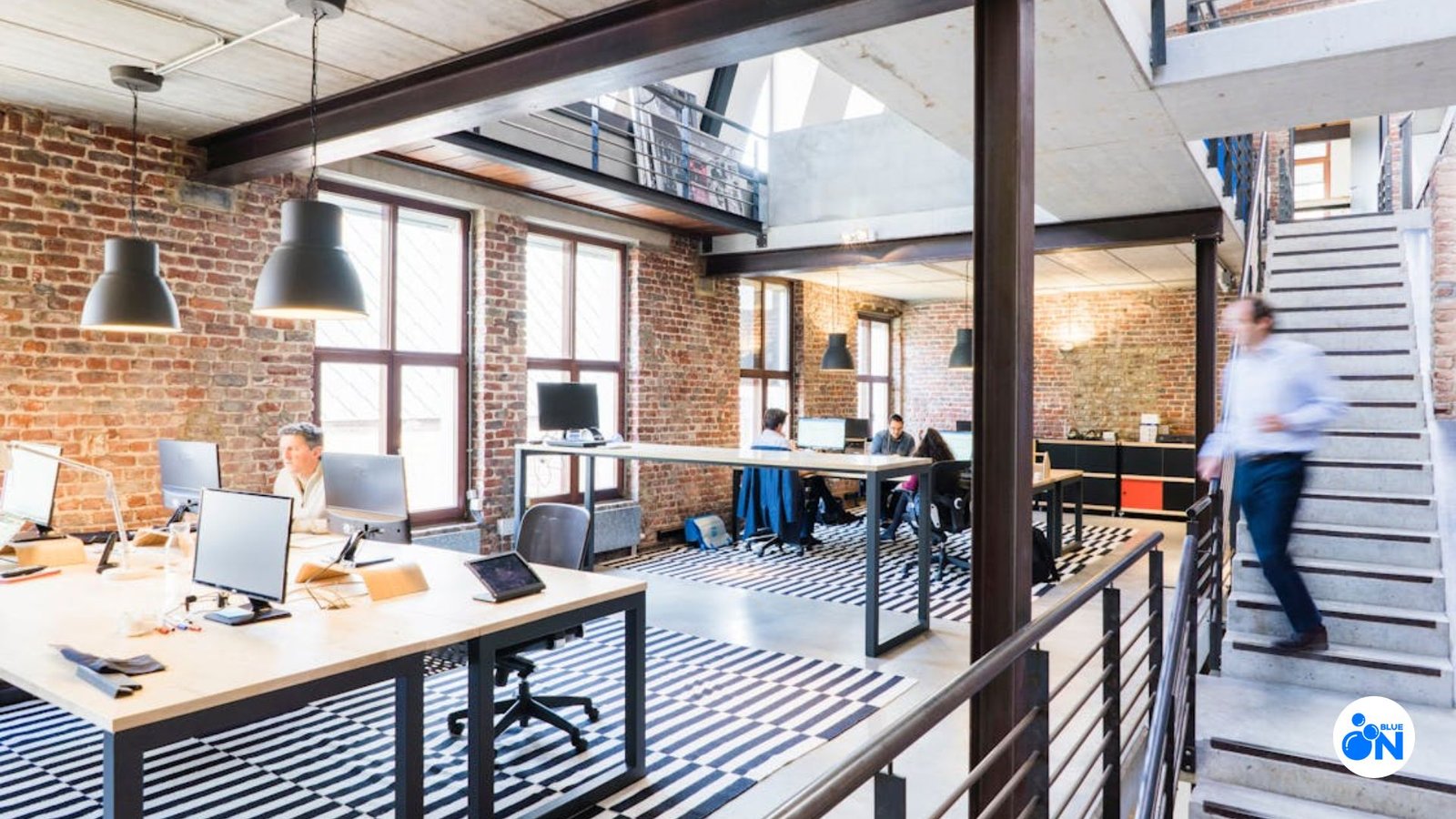 office space with tables and chairs, workers walking