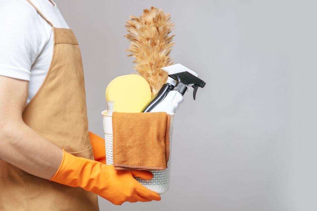 Young man holding a basket of cleaning equipment