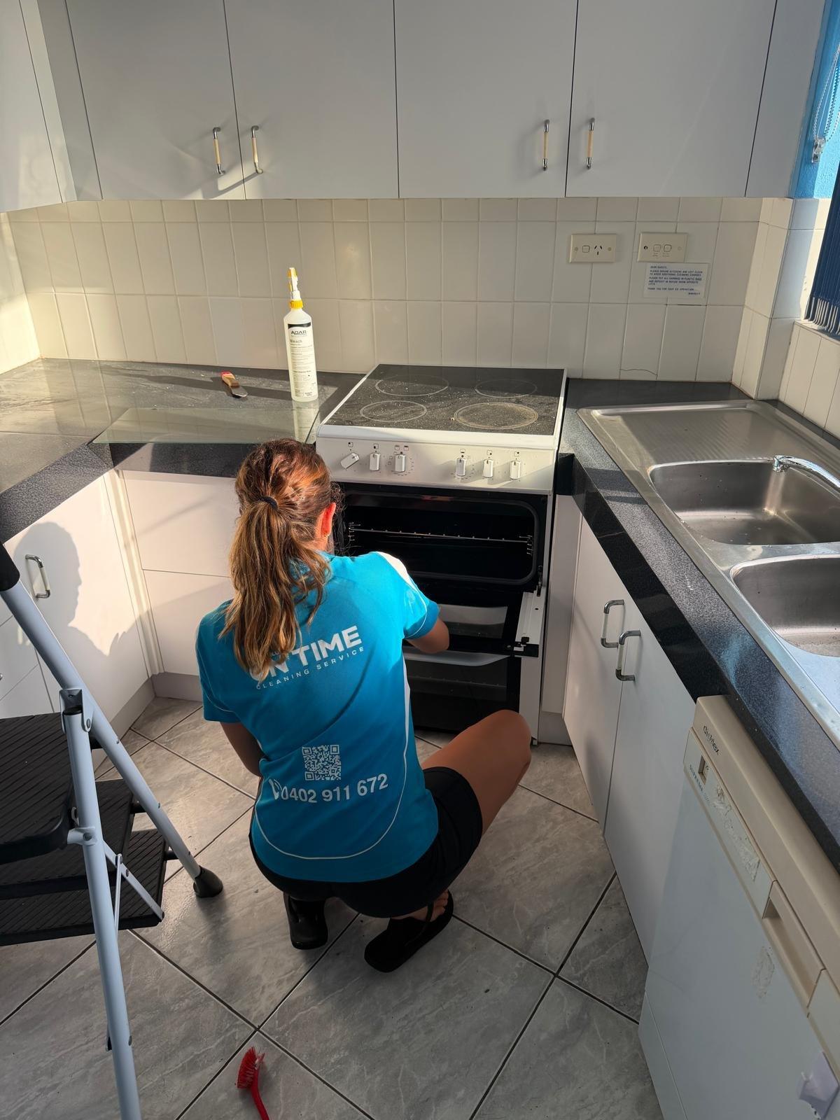 Blue On Time cleaner scrubbing an oven during end of lease cleaning on the Gold Coast